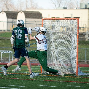 JV lacrosse player shoots ball into the net